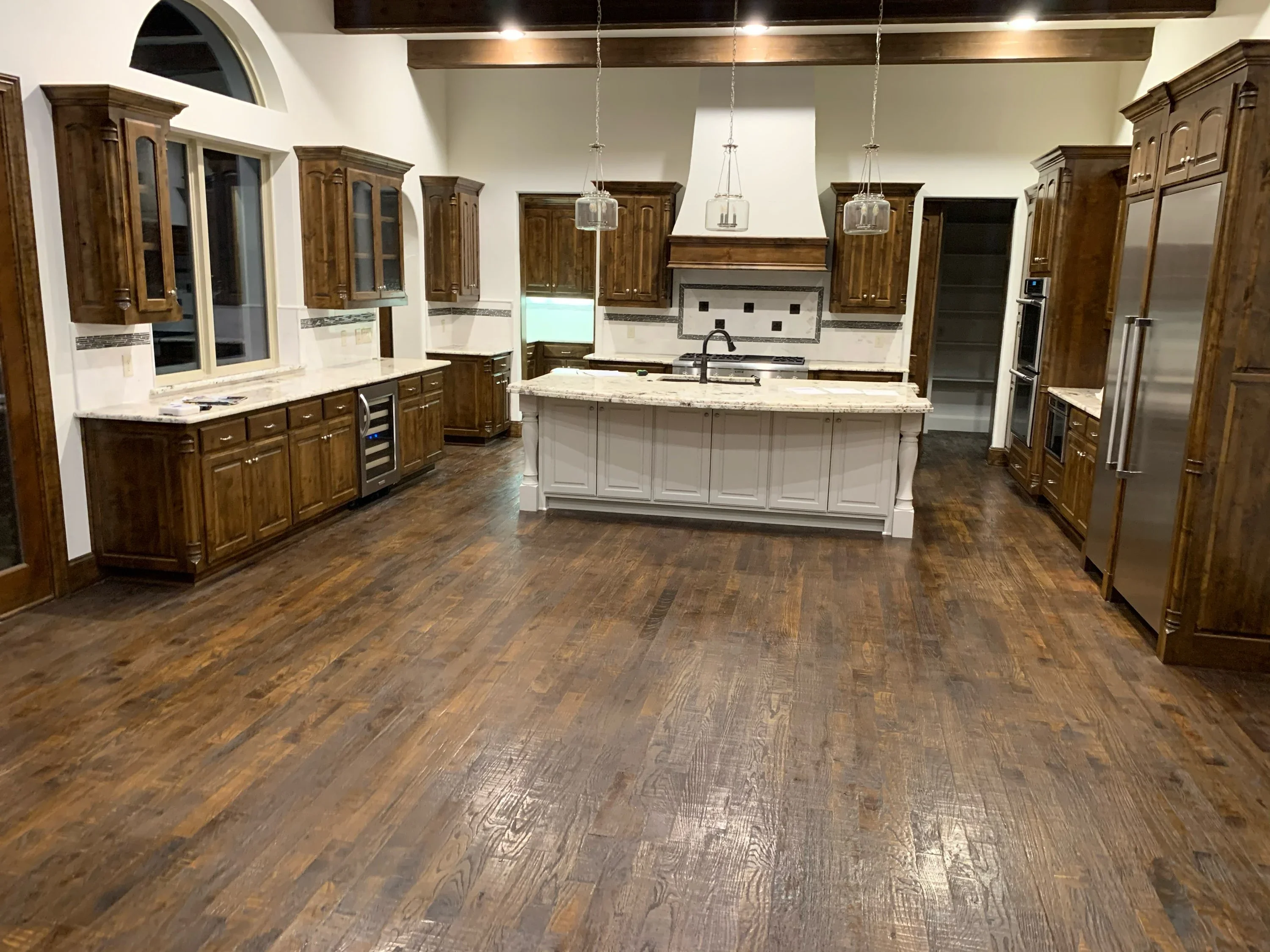 Modern kitchen with dark wood cabinets, white island, and wood-look flooring