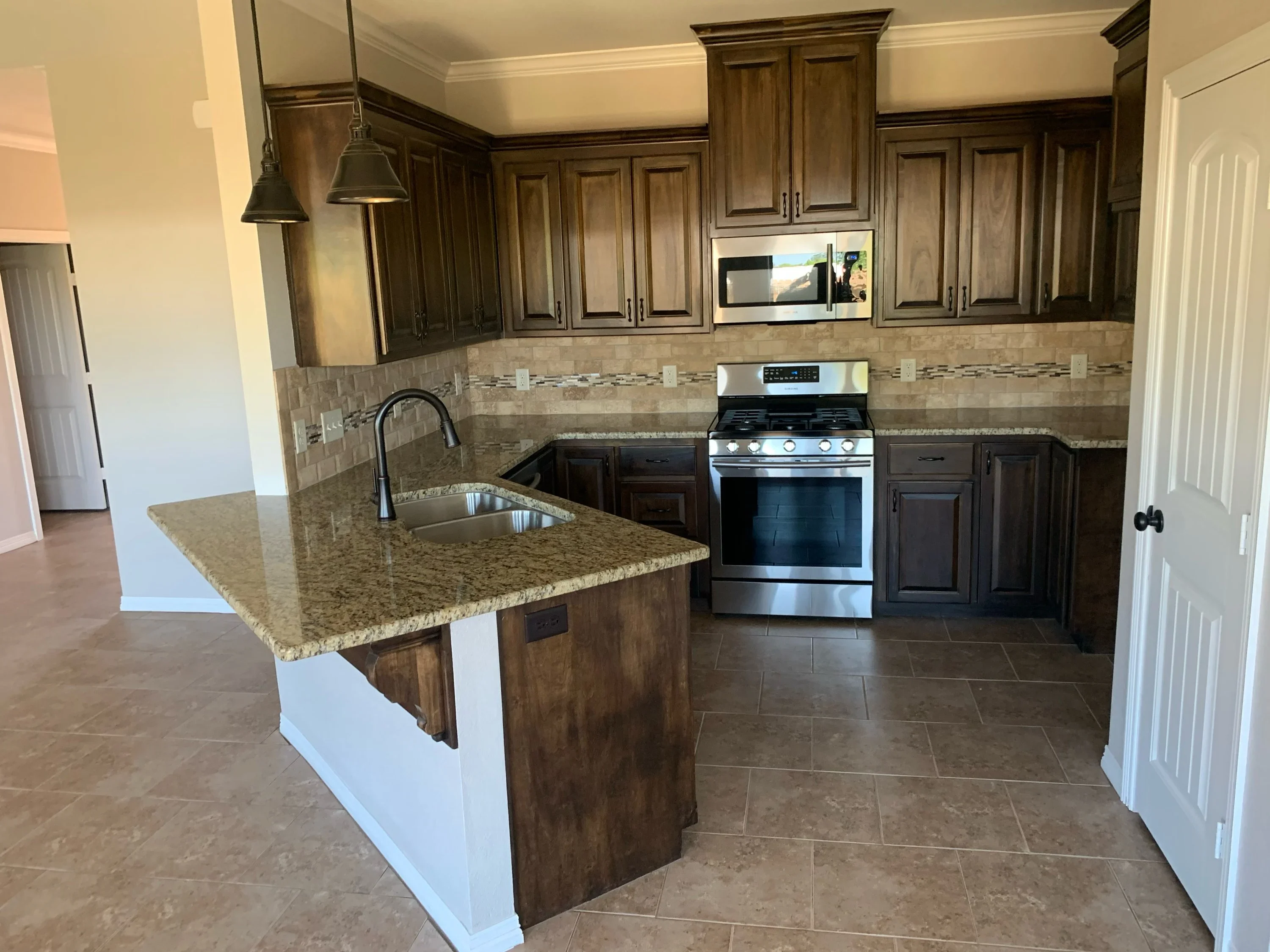 Modern kitchen with dark wood cabinets, granite counters, and custom island with pendant lights