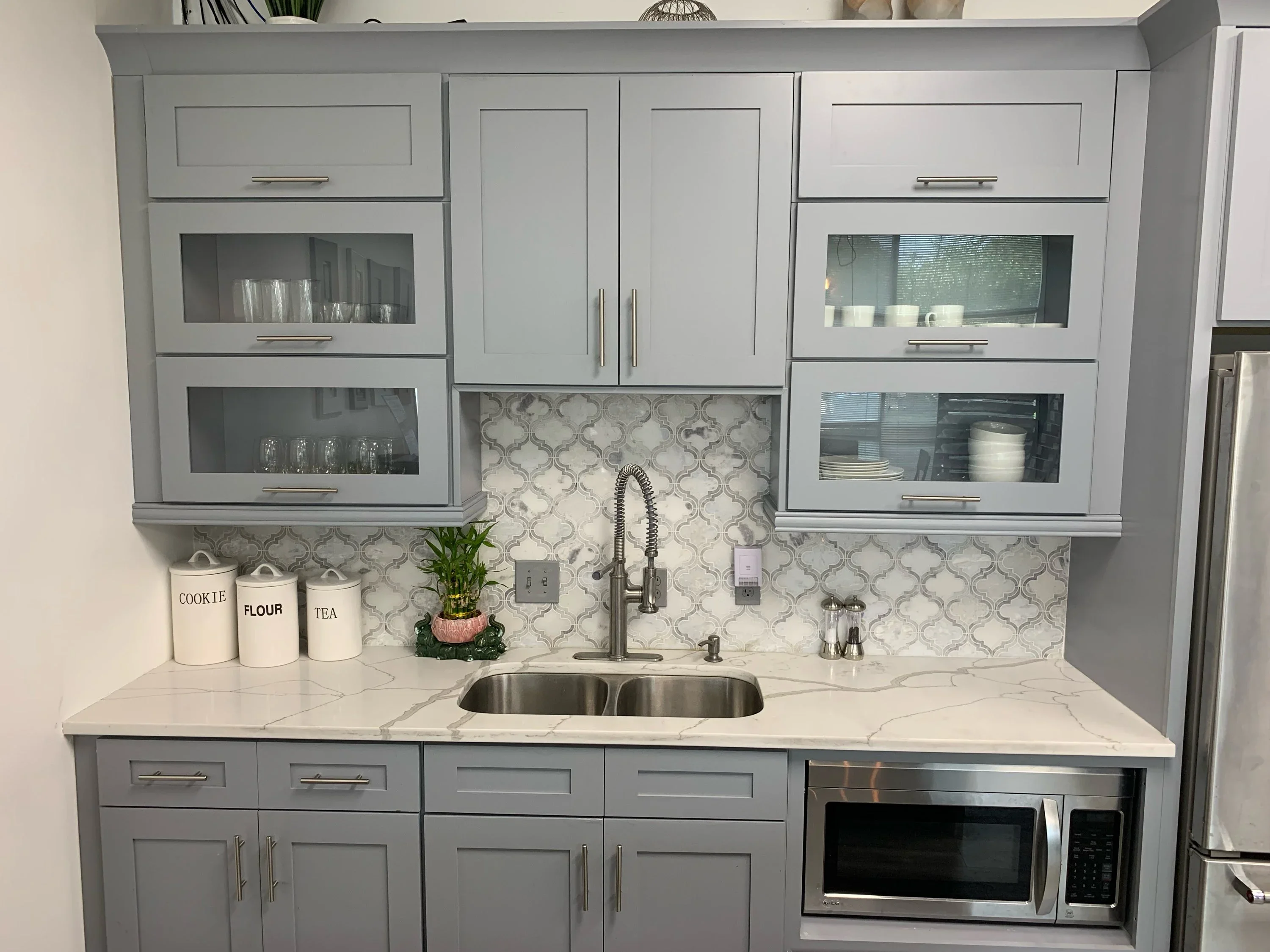 Modern kitchen with gray cabinets, marble countertops, and geometric tile backsplash